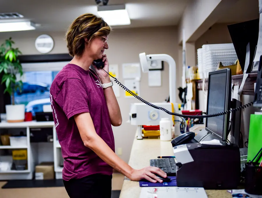 A pharmacy team member answering the telephone while working at a computer.